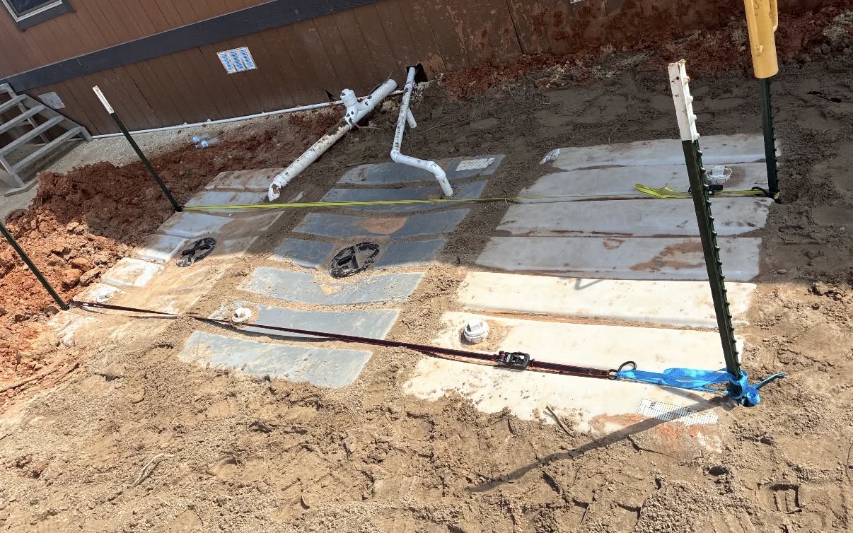 Overhead view of commercial tank installation with tie-ins, cleanout risers, and exterior building drainage piping