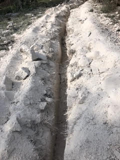 Utility trench excavated through caliche rock for commercial plumbing run