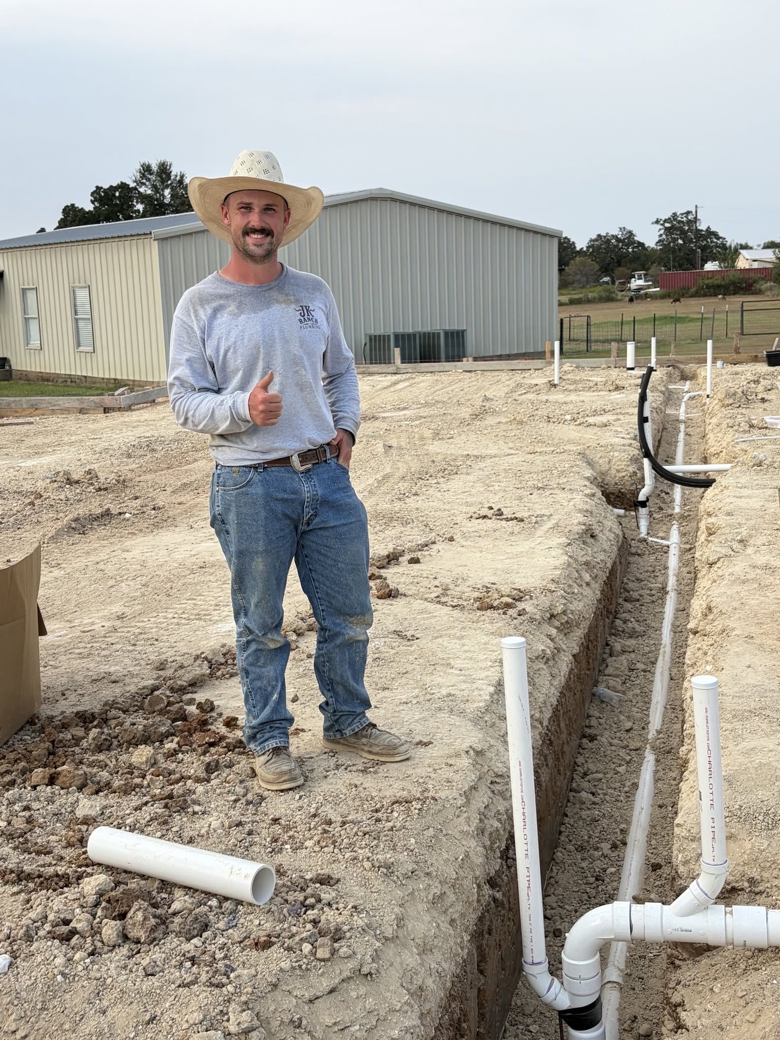 Master Plumber Jacob Pryor standing beside underground rough-in trench on a Central Texas building pad