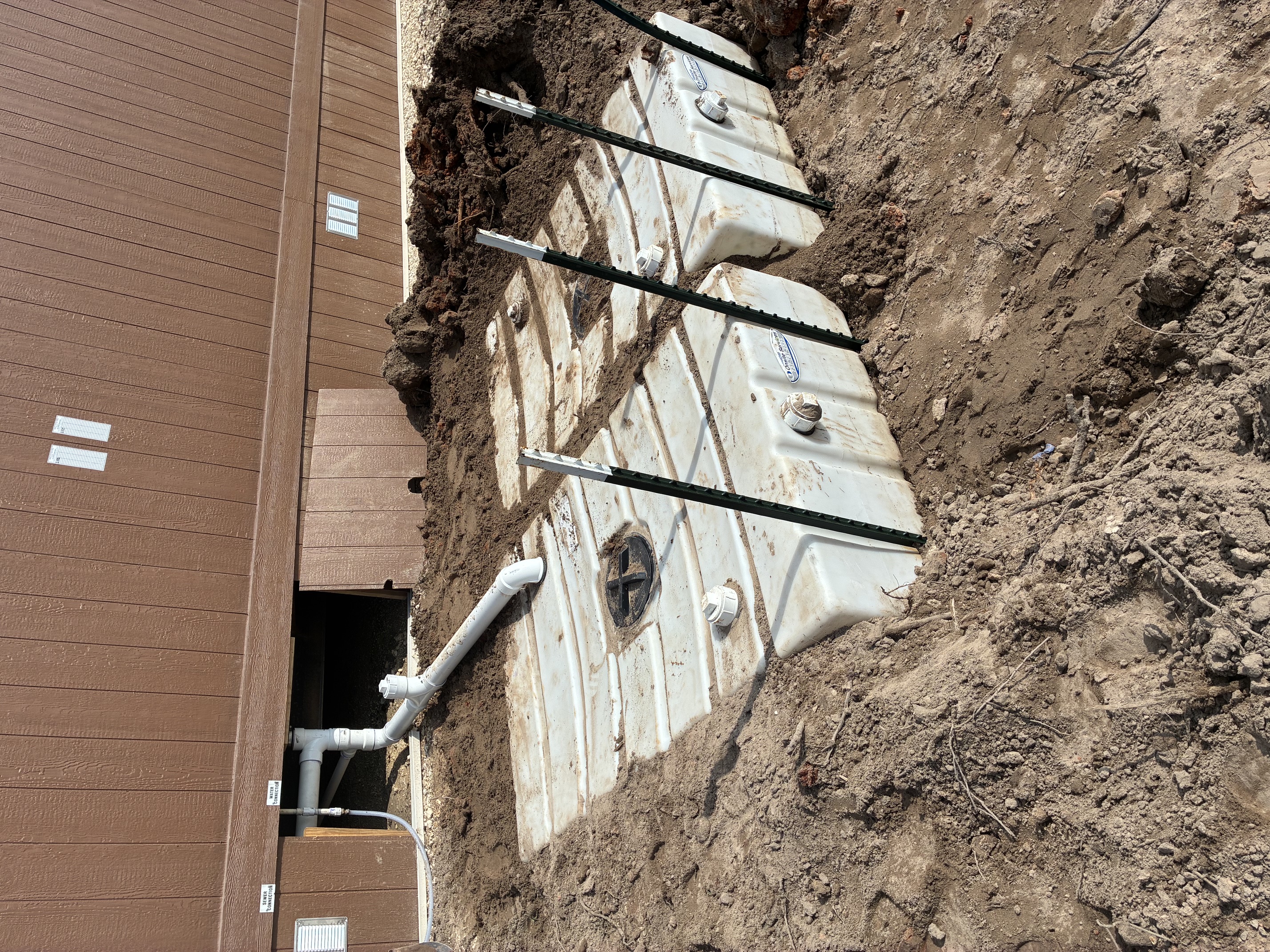 Commercial building sewer and water connections tied into exterior holding tanks with cleanout fittings