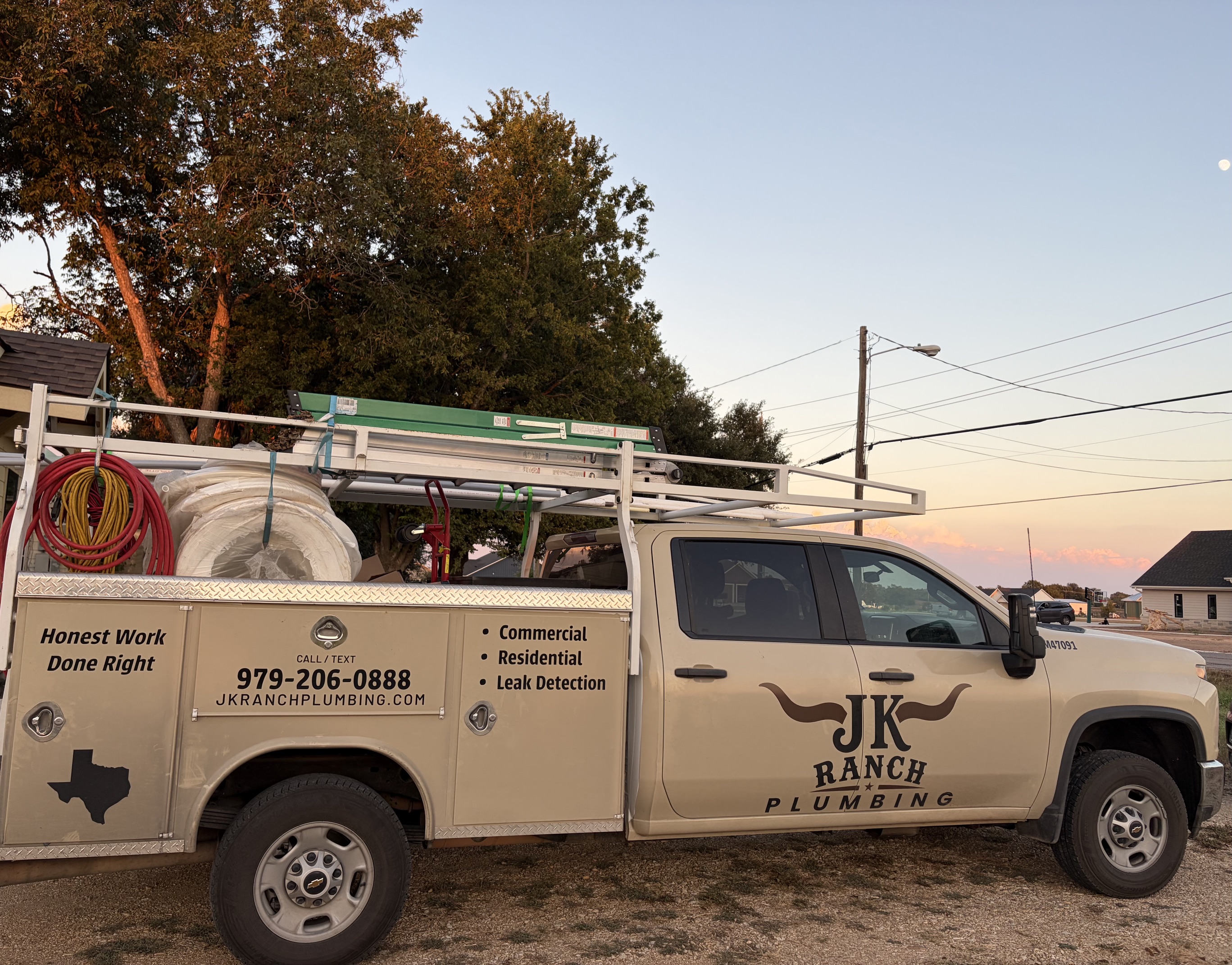 JK Ranch Plumbing truck loaded with materials at dusk showing service bed, phone number, and Texas silhouette