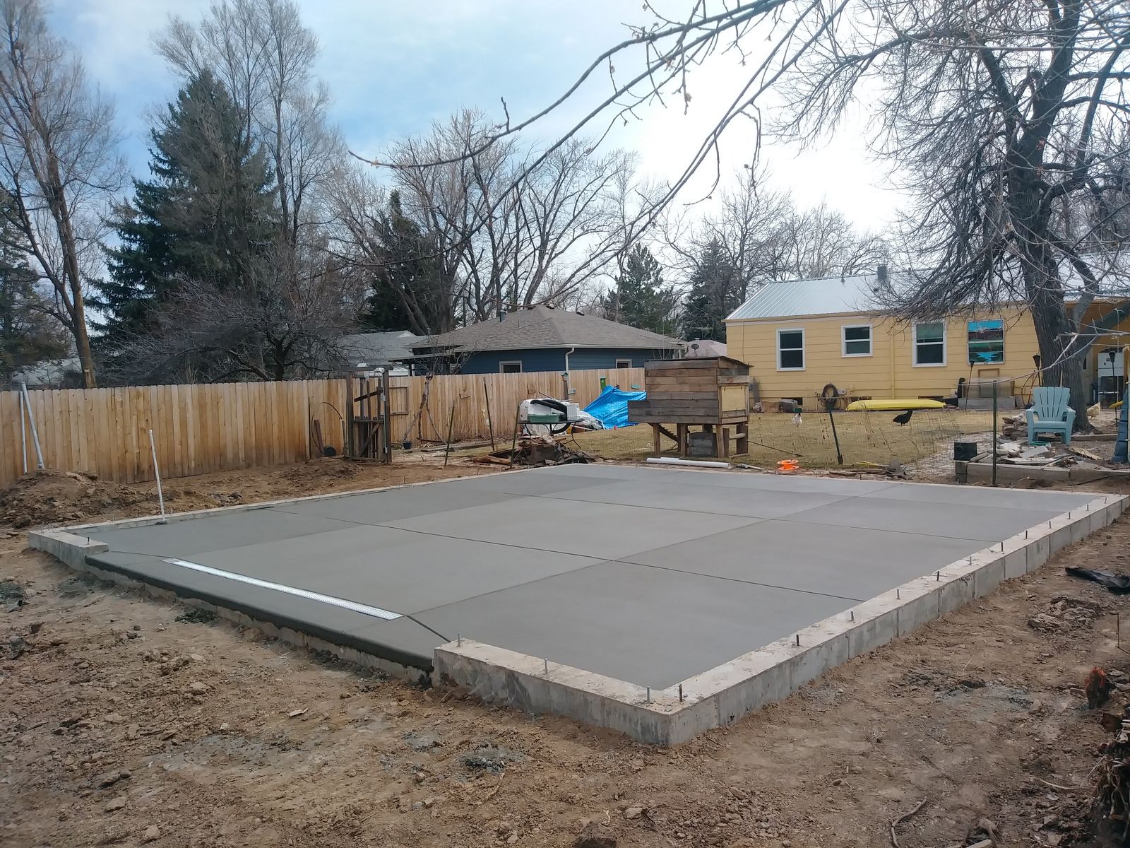 Engineered Concrete Slab Foundation with Perimeter Stem Walls, Embedded Anchor Bolts, and Integrated Drainage Channel by Happy's Concrete