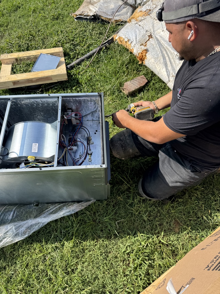 Oscar Aguirre diagnosing and servicing an open HVAC air handler unit outdoors