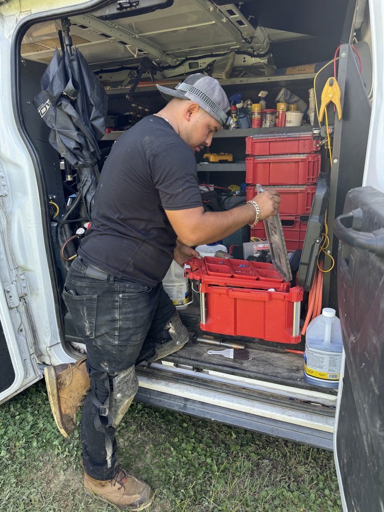 HVAC technician servicing residential outdoor condenser at a North Carolina home