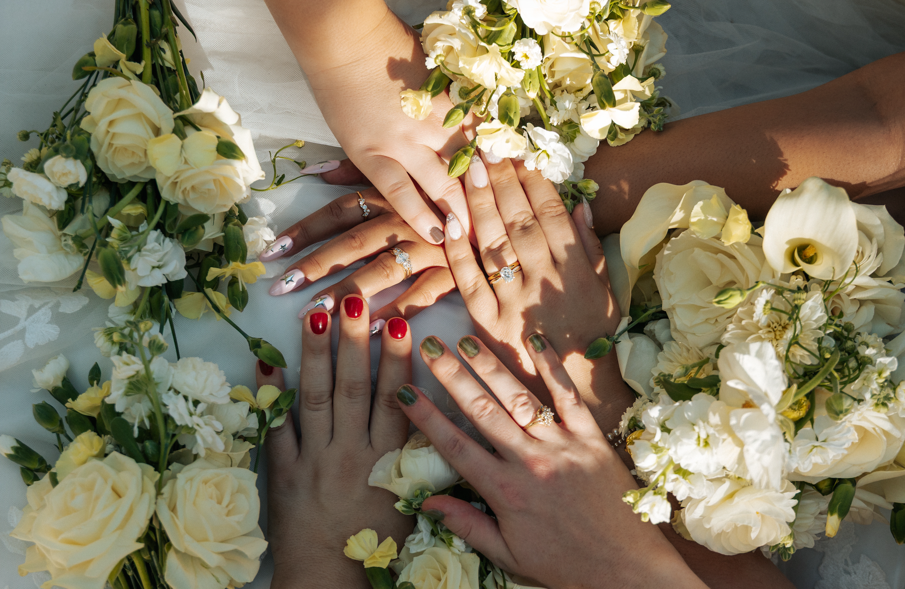 Bridal hands holding a hand-tied bouquet of garden roses, stock, and calla lilies with intricate ring styling over sheer bridal tulle