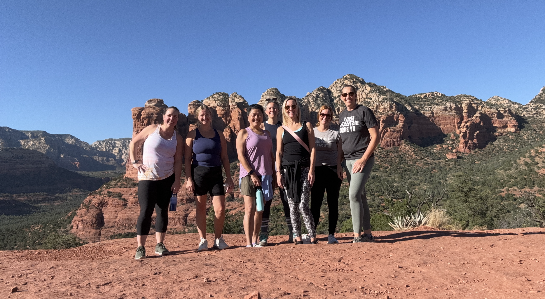 Real Wander Women community group smiling together on a sunny red rock hiking trip