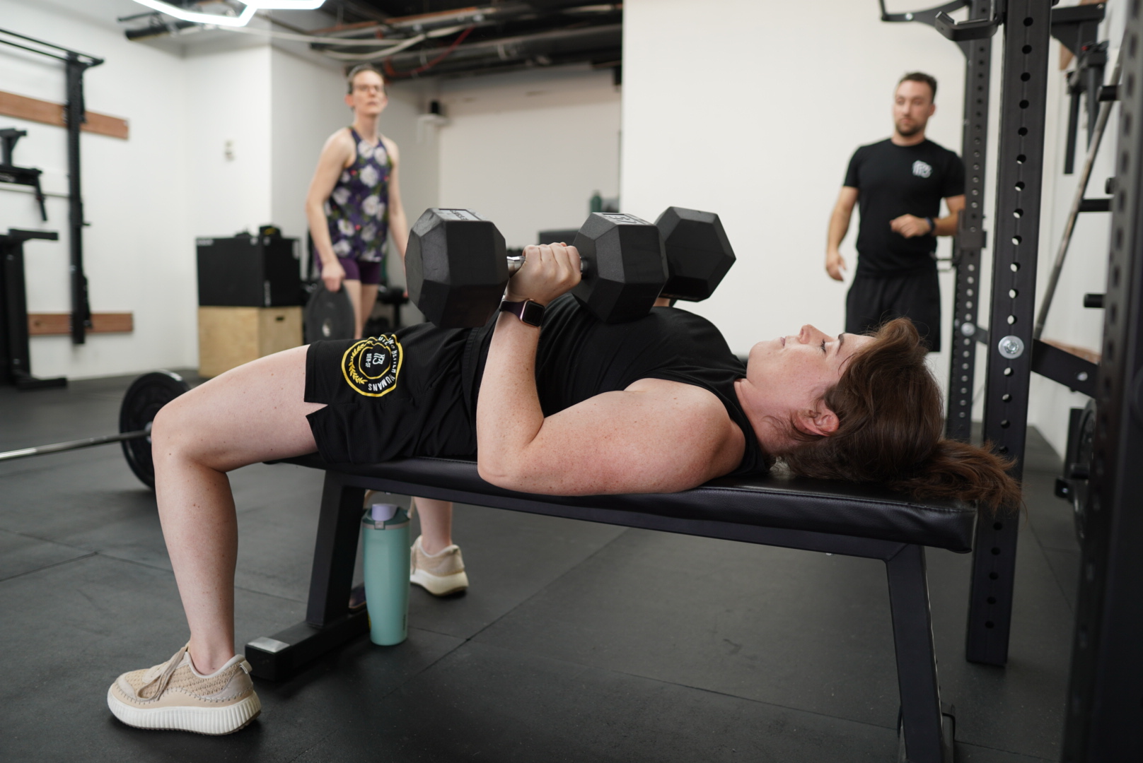 Coach actively monitoring dumbbell bench press technique and form