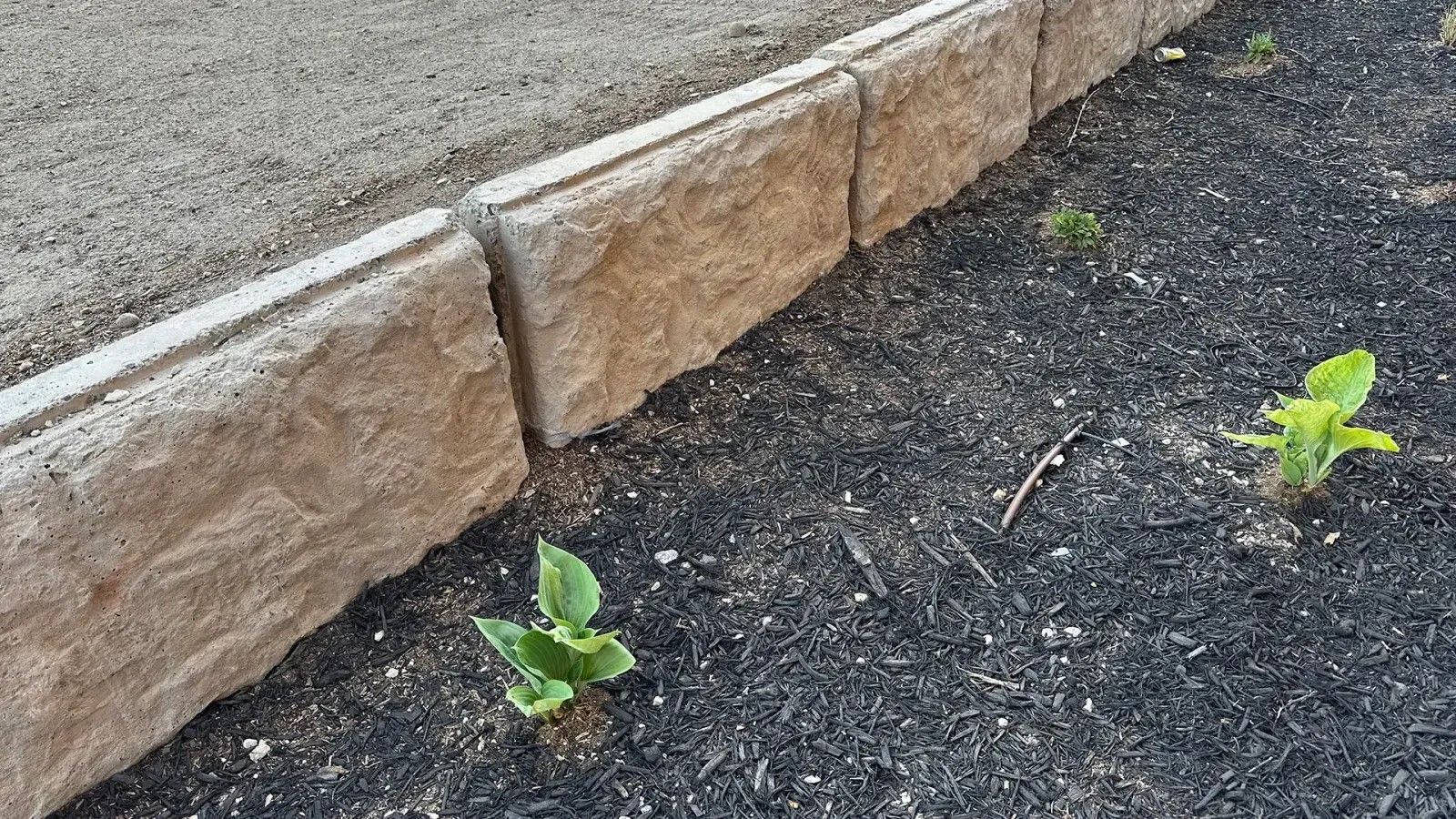 Modern concrete block retaining wall framing a paver patio with outdoor seating in Herriman, UT