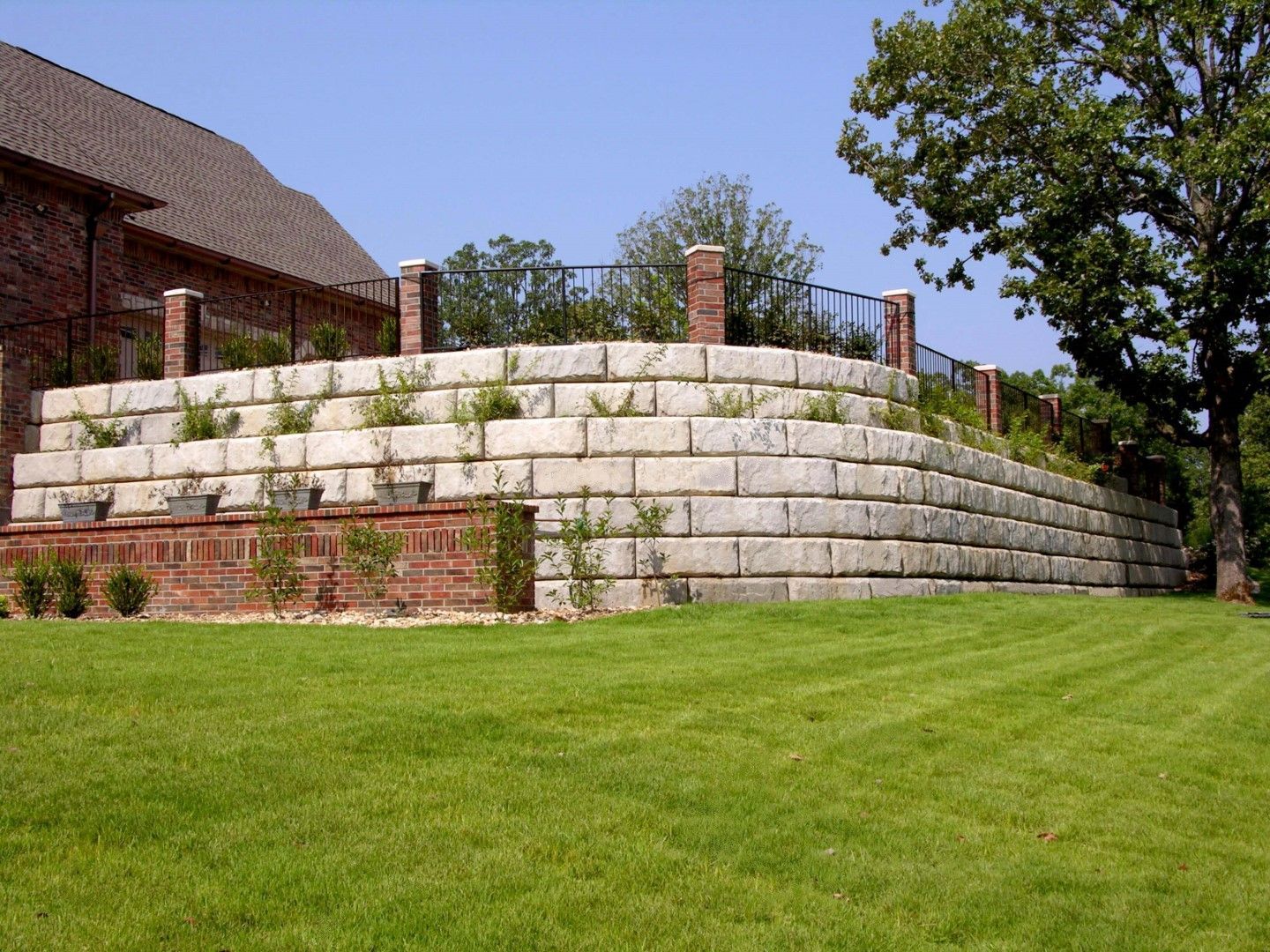 Two-tier concrete block retaining wall built into a sloped residential yard with fresh sod in Herriman, UT