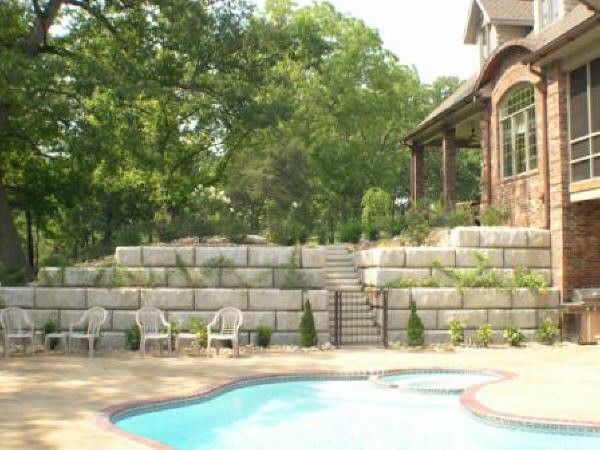 Newly constructed concrete block retaining wall supporting a raised garden bed with fresh mulch in a residential backyard in Herriman, UT