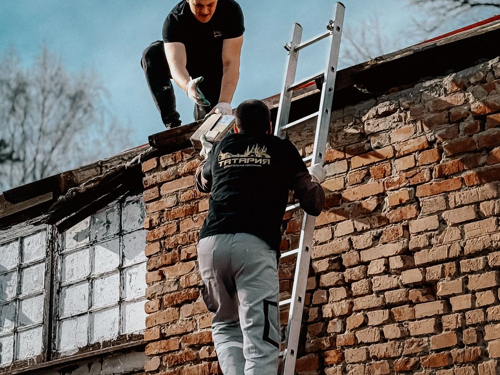 Two roofers working from a ladder on a residential roof edge