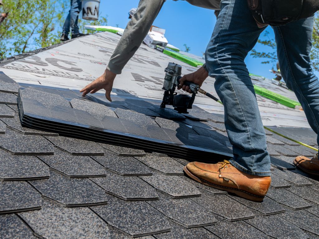 Roofer nailing architectural shingles into place on a residential roof deck