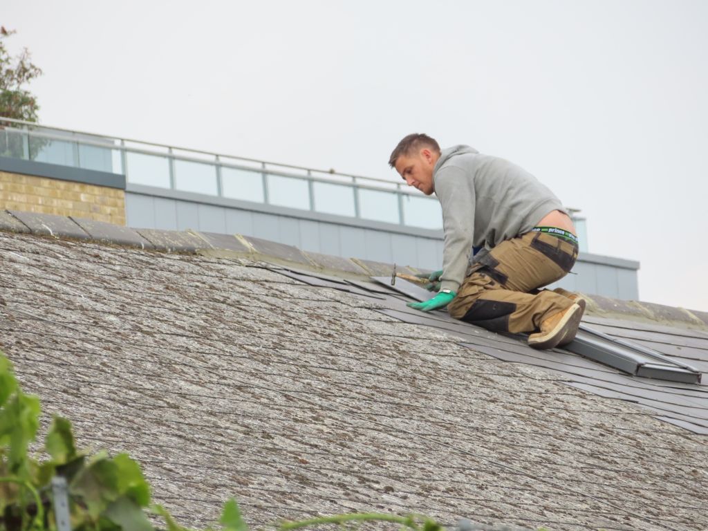 Roofing technician kneeling to seal a seam on a low-slope commercial roof