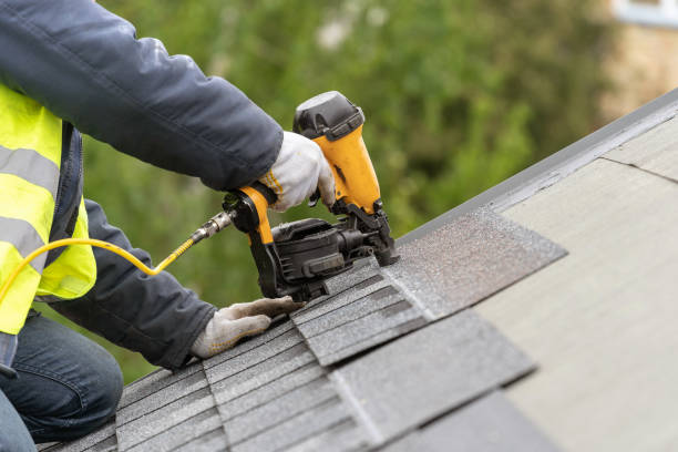 Roofer installing architectural shingles with a coil nailer on a residential roof