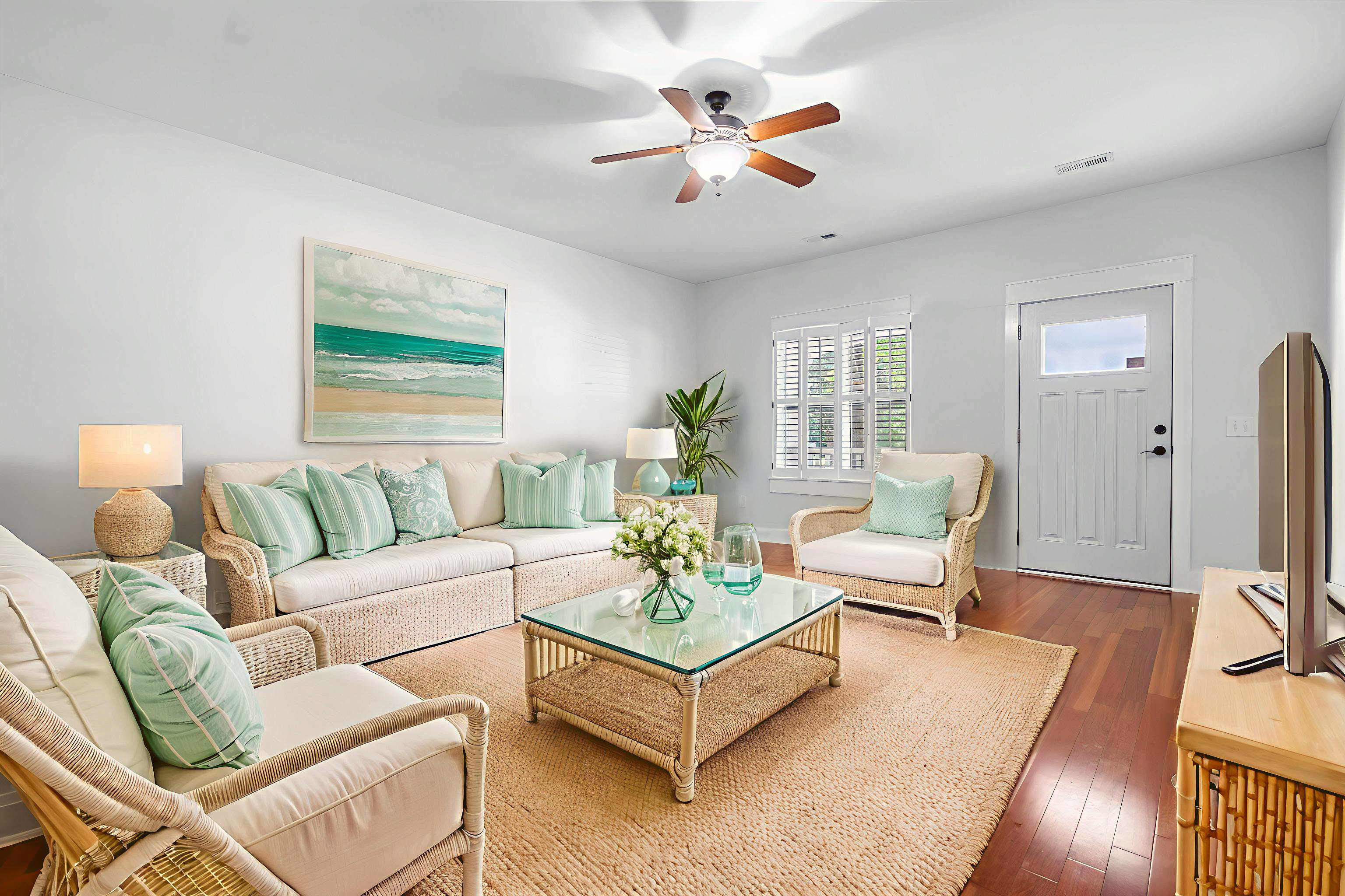 Virtually staged coastal living room with wicker seating, area rug, coffee table, and coastal artwork
