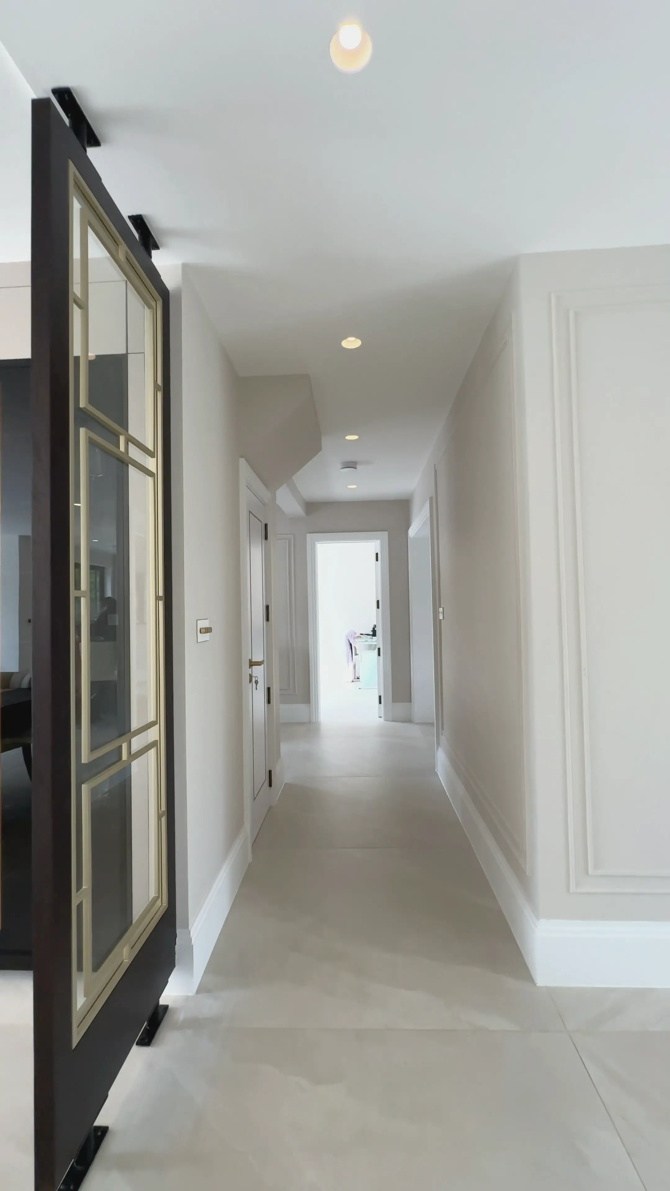 Renovated hallway with bespoke sliding glazed door and refined wall panelling in a Surrey home