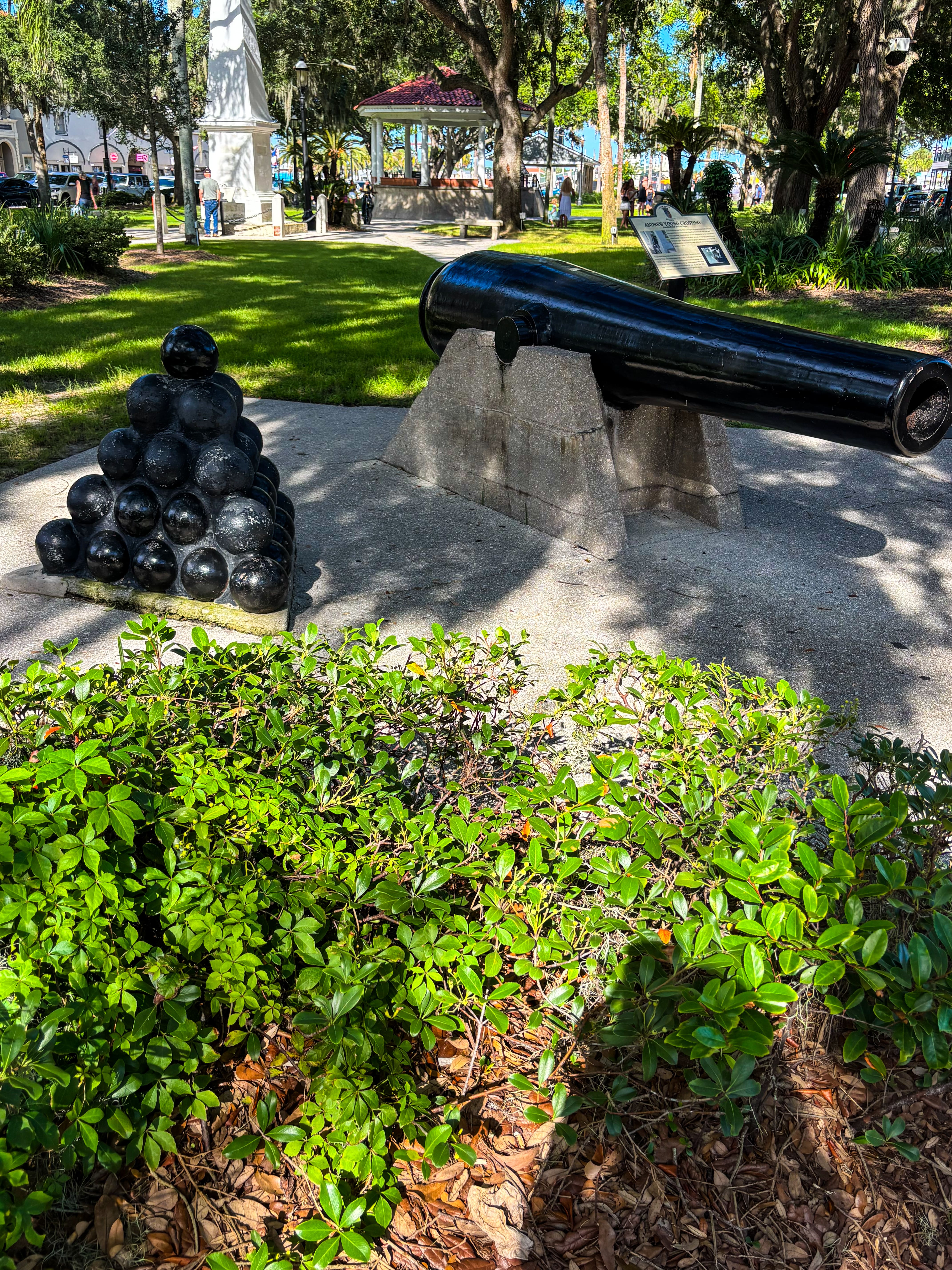 Historic cannon and stacked cannonball monument on the shaded park grounds of St. Augustine