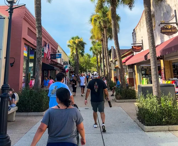 St. George Street bustling pedestrian historic district with colonial shops, flags, and palm trees