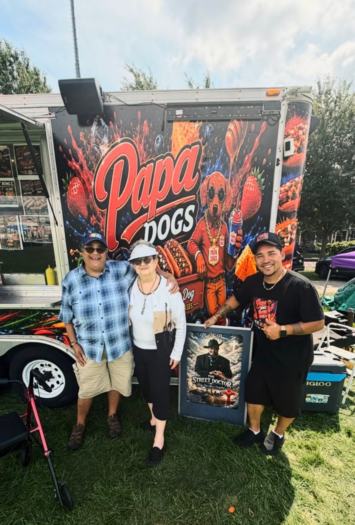 Three customers posing together in front of the Papa Dogs trailer mural