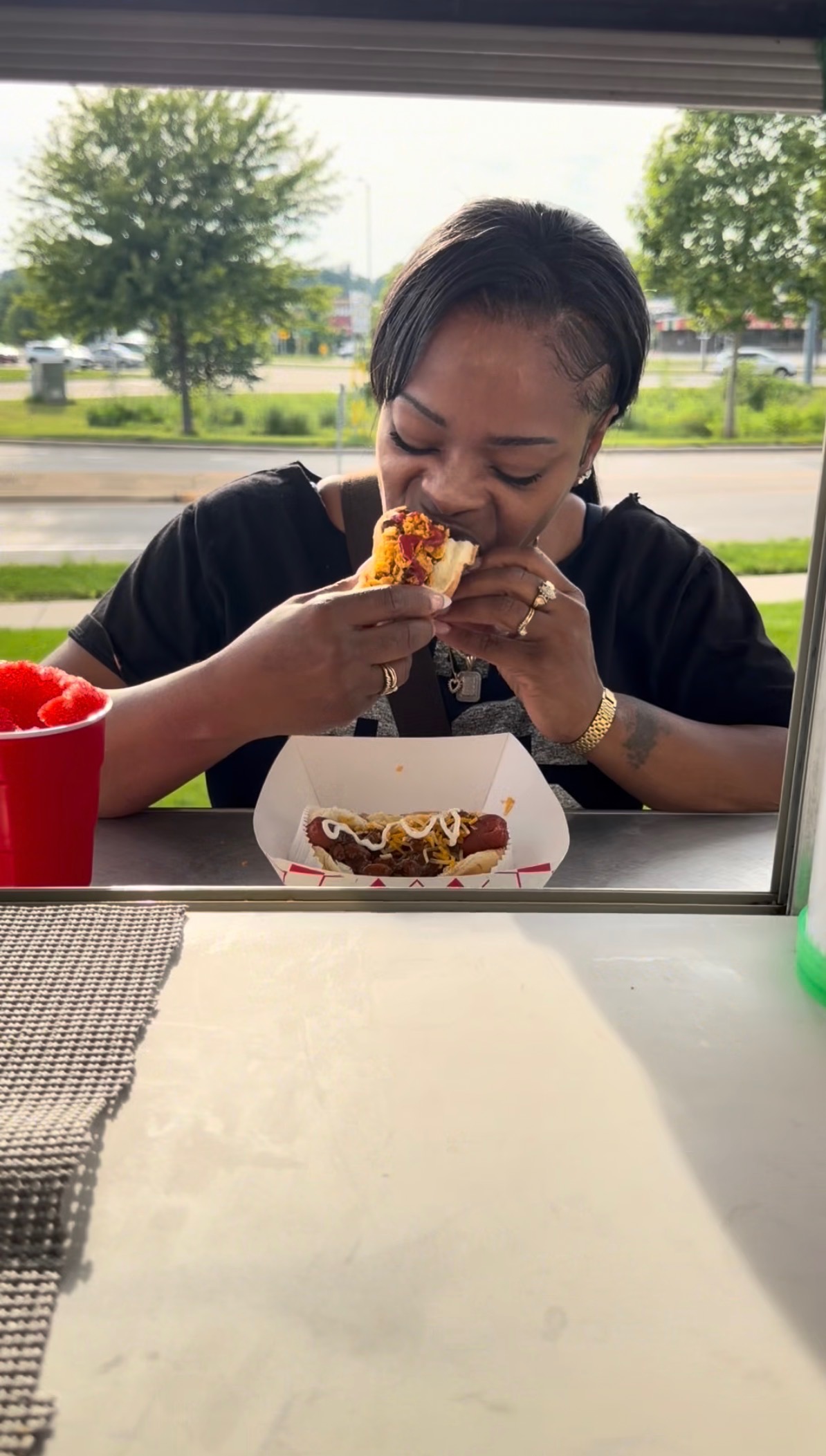 Customer taking a bite of a loaded chili cheese dog at the Papa Dogs trailer window