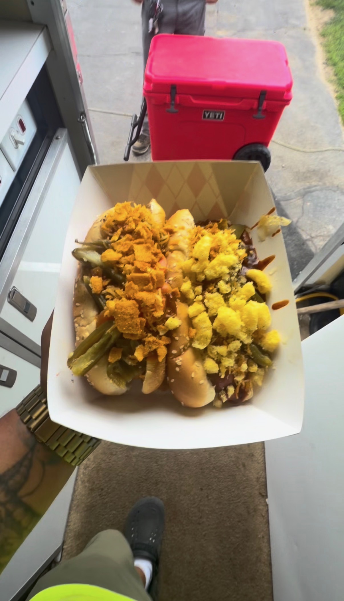 Two loaded hot dogs in a takeout tray next to a Papa Dogs slushy and a red Yeti cooler