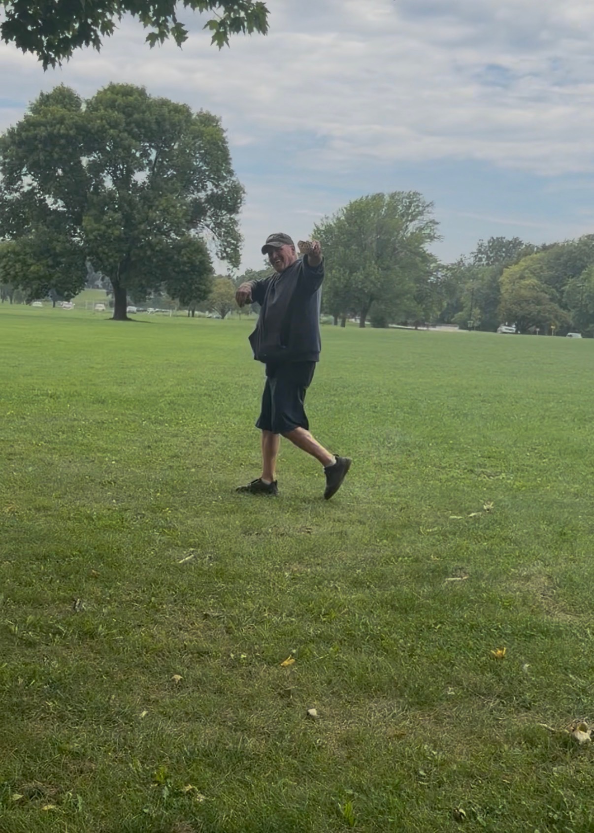 Customer pointing and smiling while holding a Papa Dogs hot dog in the park
