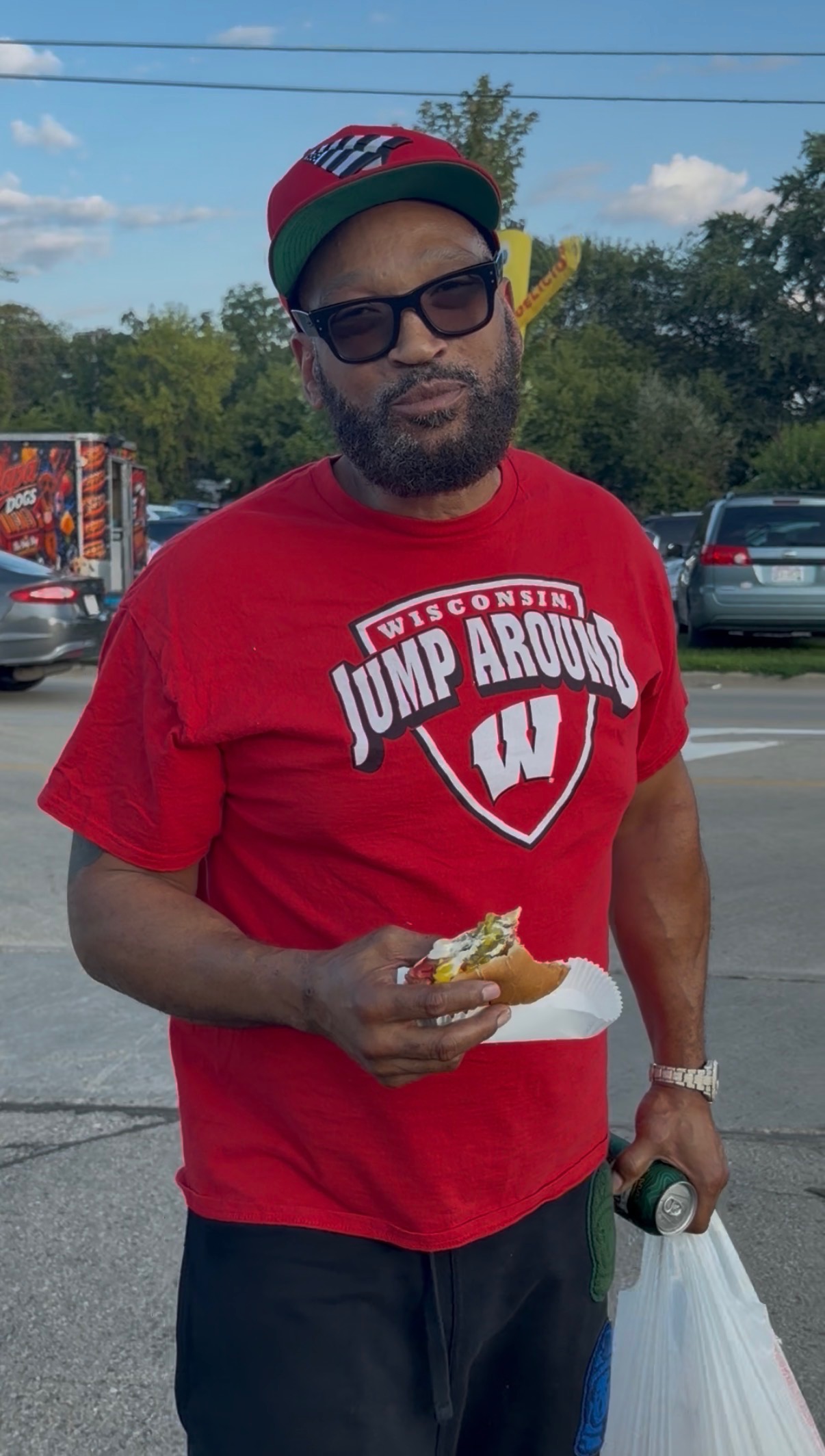 Customer in a Wisconsin Jump Around shirt enjoying a loaded Papa Dogs hot dog