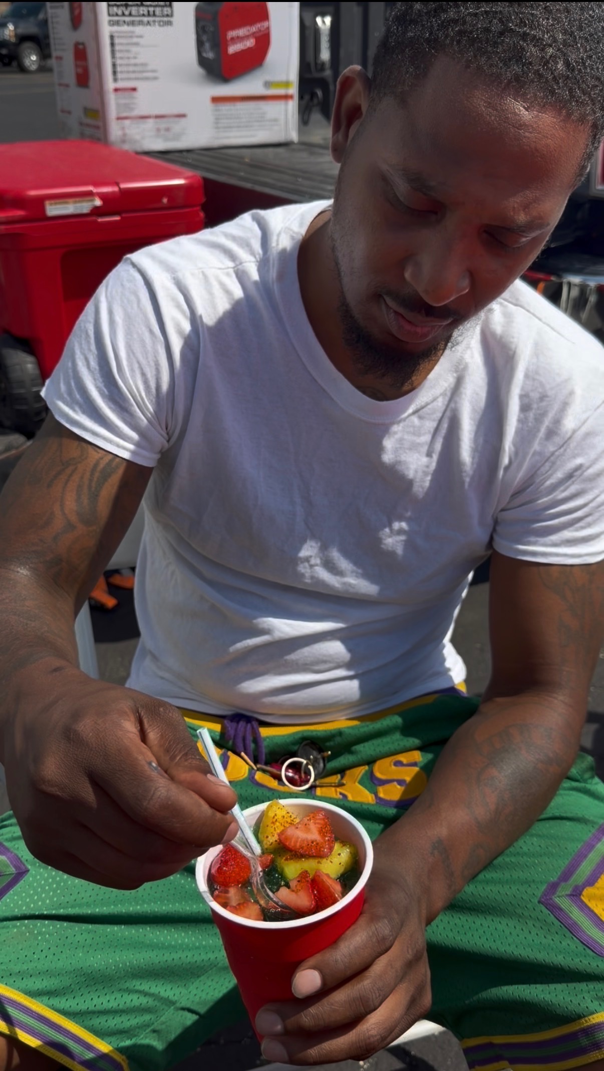 Customer enjoying a fresh fruit cup with strawberries and pineapple at an event