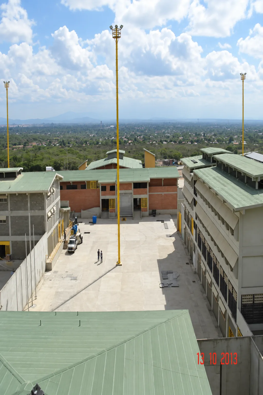 Vista superior de módulos terminados, patios internos pavimentados y torres de iluminación de alta potencia para el recinto