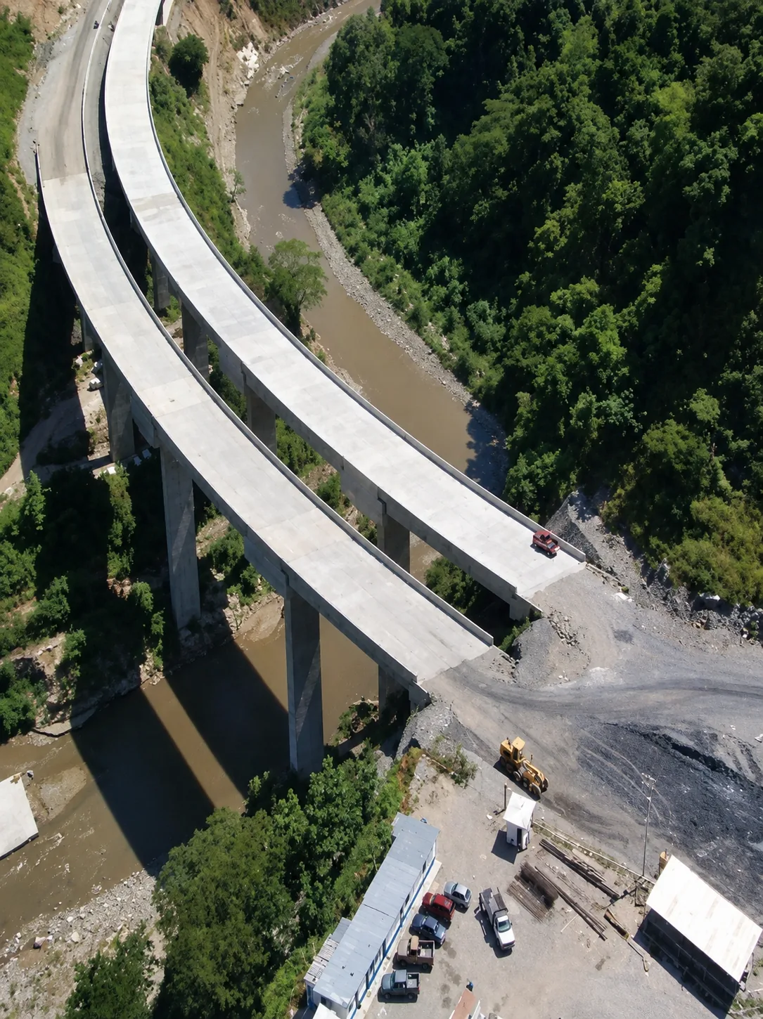 Vista aérea cenital de los dos viaductos paralelos sobre el cañón del Río Grande, accesos viales y campamento de maquinaria pesada
