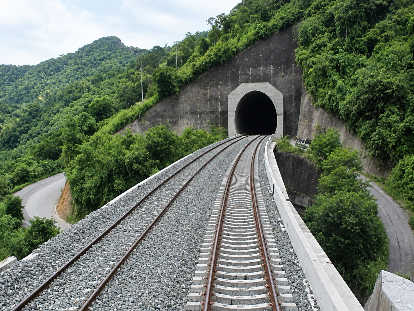 Trazado ferroviario en viaducto y embocadura de túnel: superestructura de vía en balasto sobre losa de concreto con traviesas monobloque y encauzamiento en ladera montañosa