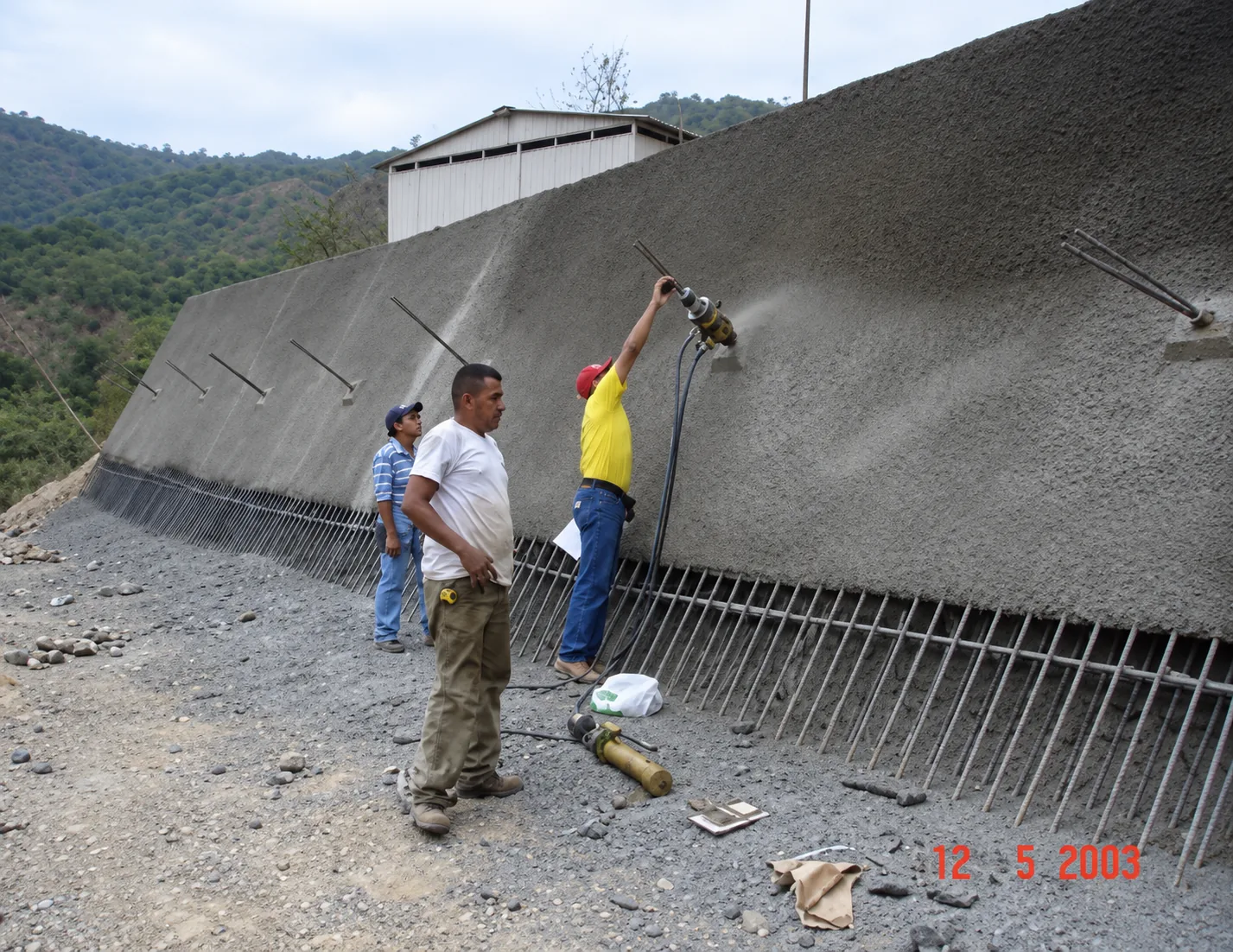Personal técnico de Vialpa ejecutando fijación e inyección de anclajes en pantalla atirantada sobre ladera rocosa (Registro en obra: mayo 2003)