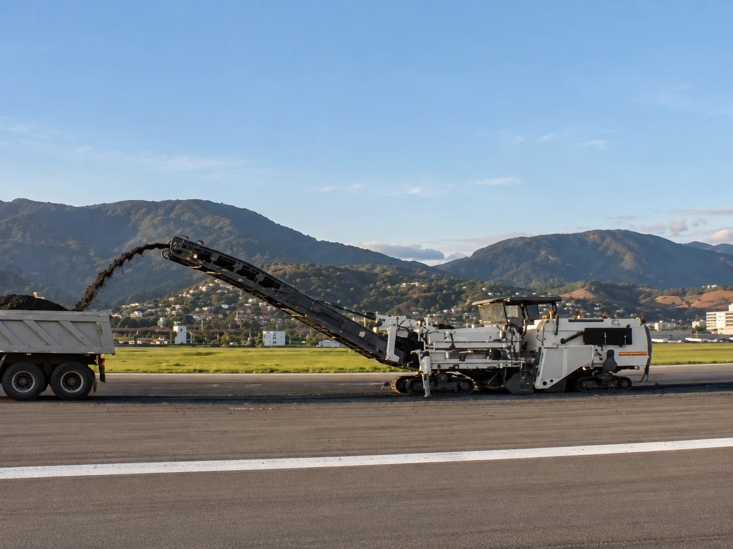 Fresadora de pavimento de alta capacidad sobre orugas con sistema de descarga continua en camión volquete, retirando la capa deteriorada de 15 cm de la pista original