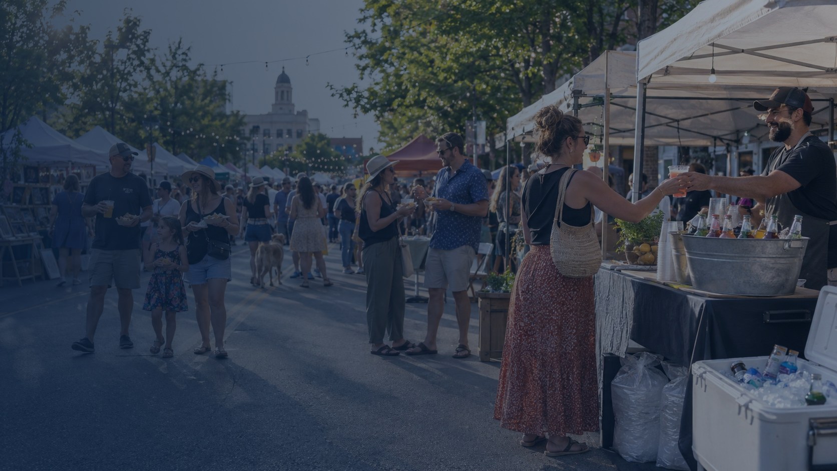 Outdoor festival vendor booth with beverage tubs and coolers stocked with ice and cold drinks