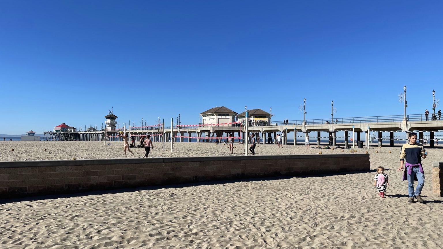 Huntington Beach Pier with beach volleyball nets, sunny blue skies and Pacific Ocean