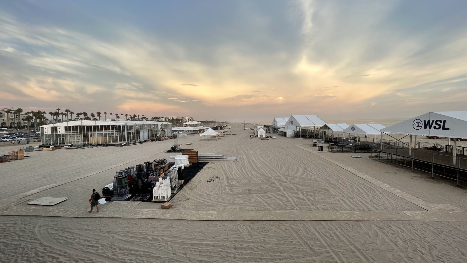 Pre-Huntington Beach Event setup on the beach sands featuring WSL tents, event staging and coastal sunset sky