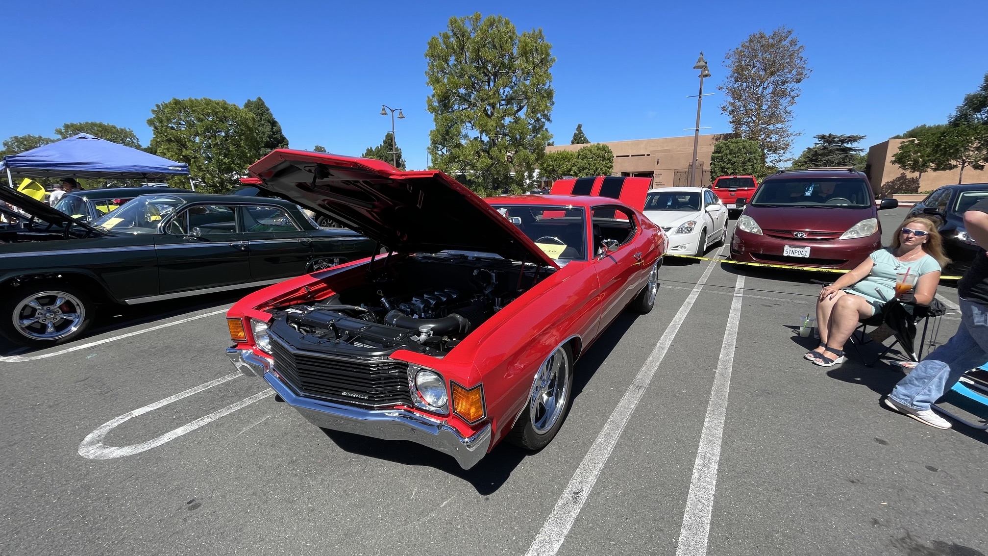 Vibrant red classic American muscle car with open hood on display at Huntington Beach St. Vincent de Paul car show