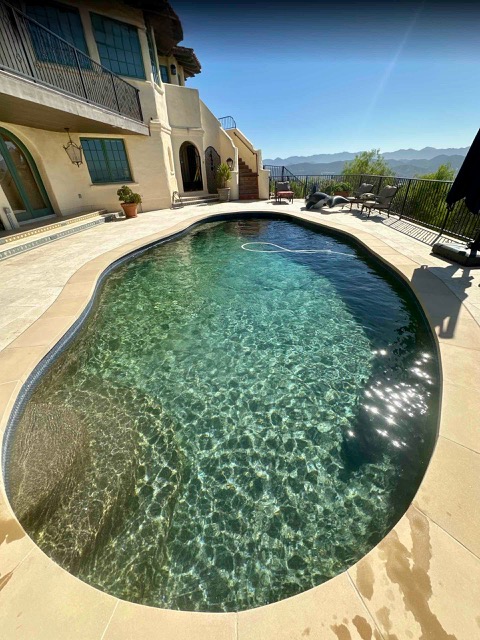 Freeform backyard swimming pool with dark plaster finish and mountain view