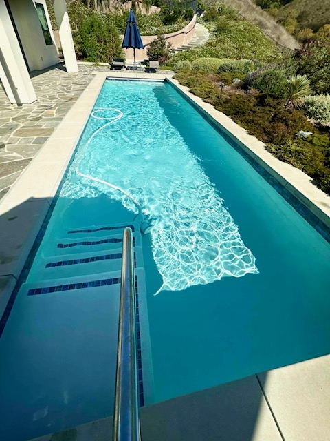 Lap pool with entry steps, handrail, and clear blue water