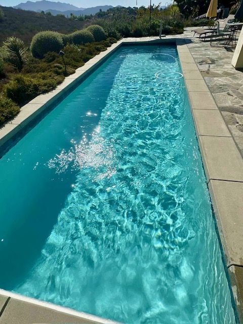 Rectangular swimming pool with clear turquoise water and stone coping