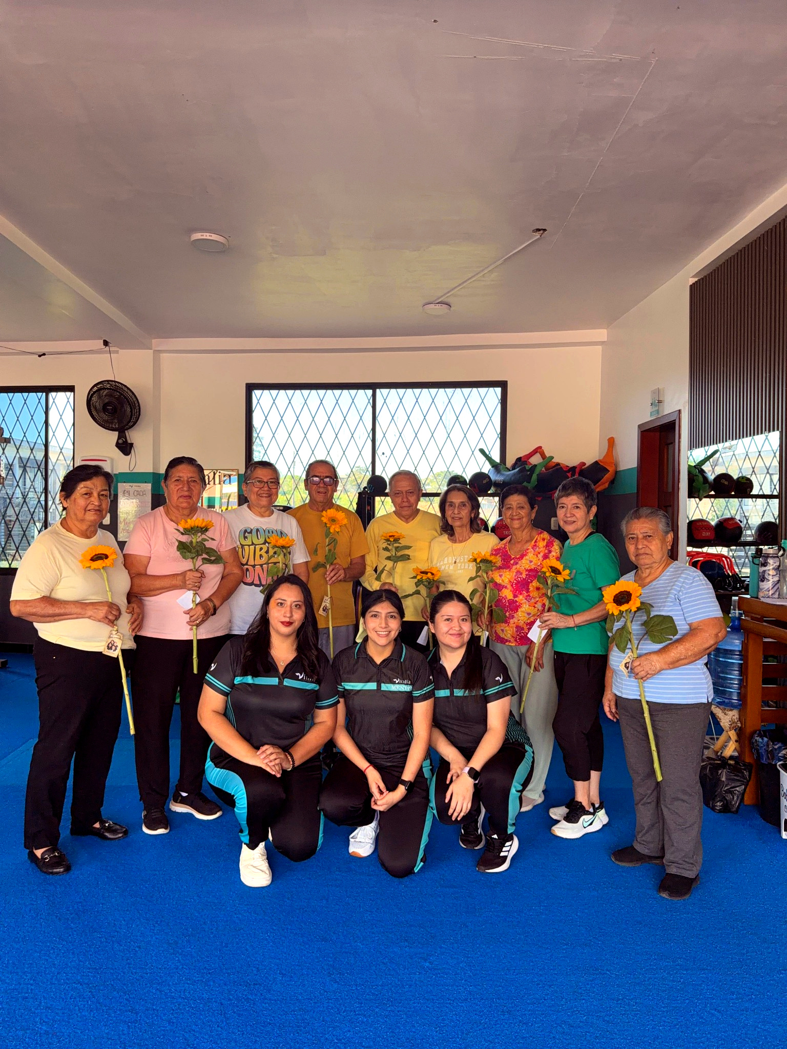 Miembros de Vitalia Club junto a su equipo profesional celebrando con flores en el club