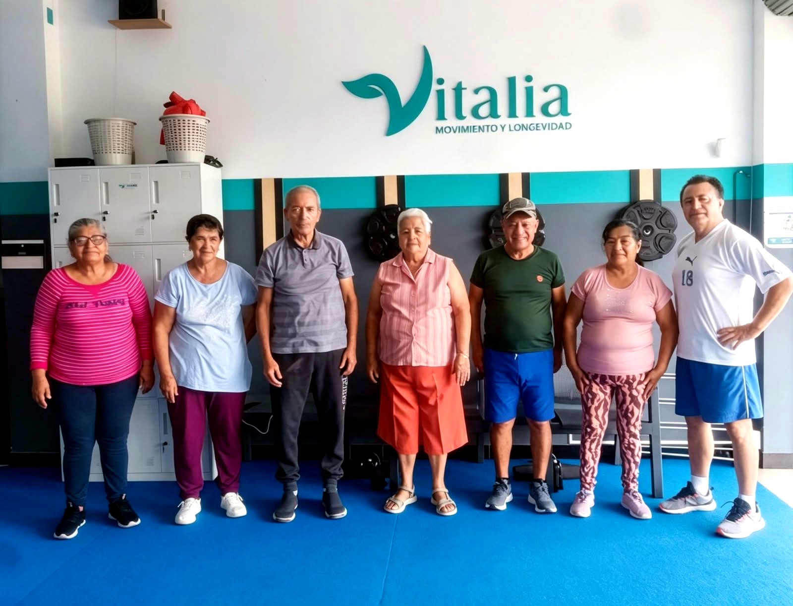 Miembros de Vitalia Club reunidos en las instalaciones del club frente al logotipo oficial