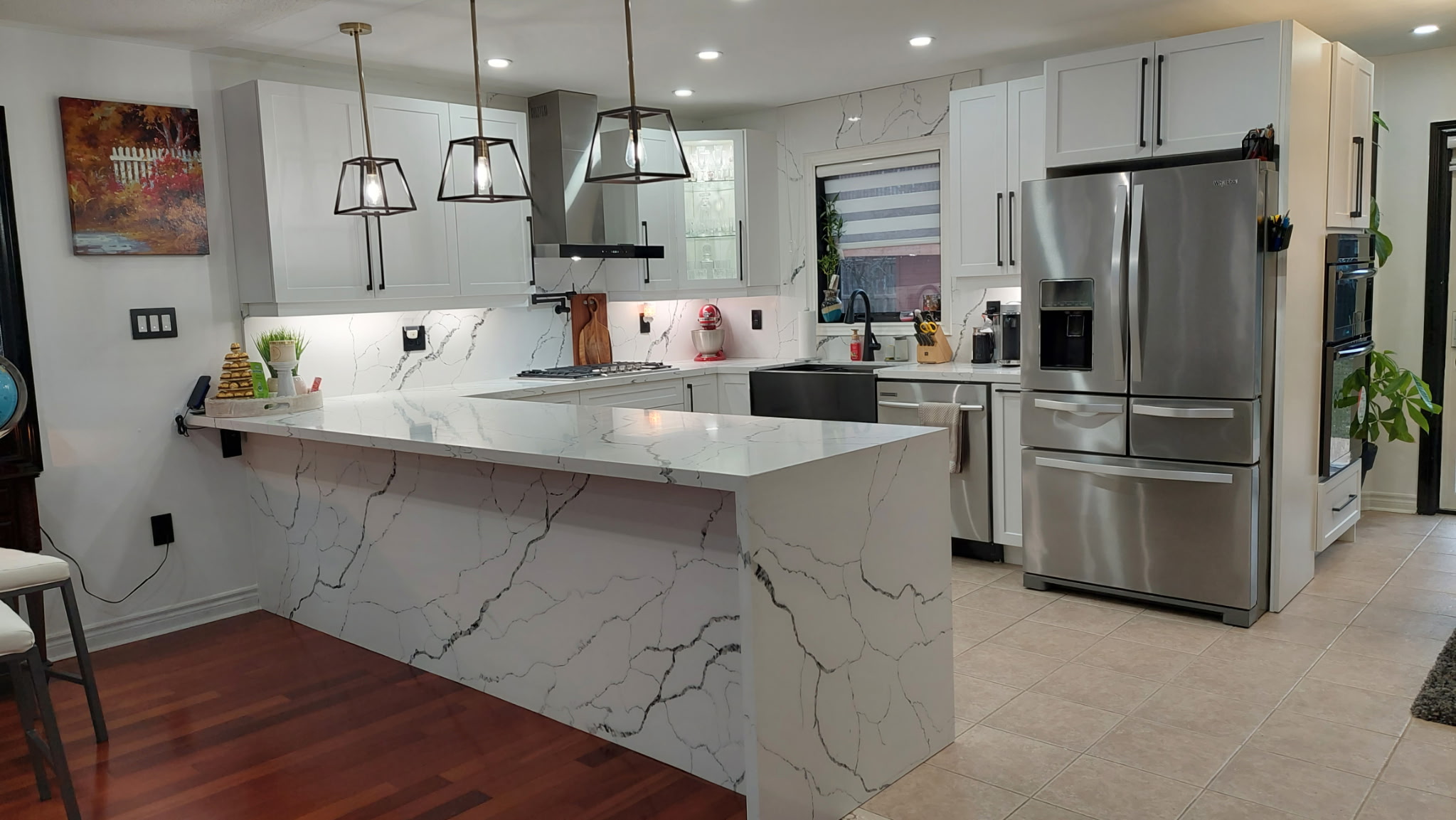 Custom waterfall quartz countertop island with full-height stone backsplash installed in a modern kitchen