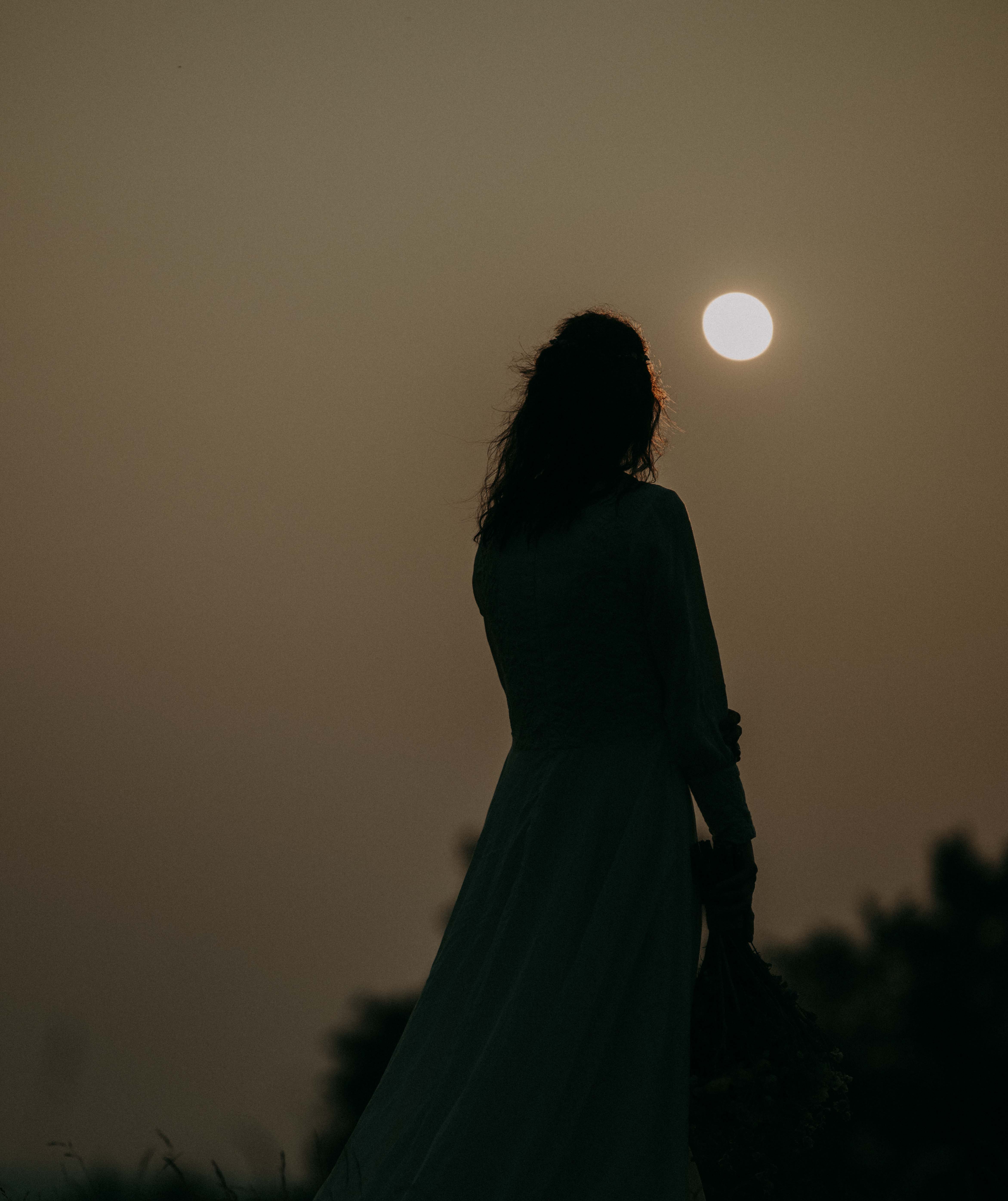 Silhouetted bride against a warm sunset sky