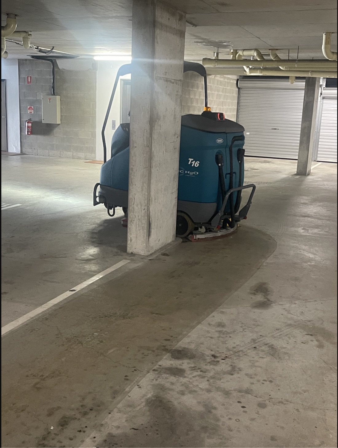 Ride-on vacuum scrubbing the floor of a basement car park