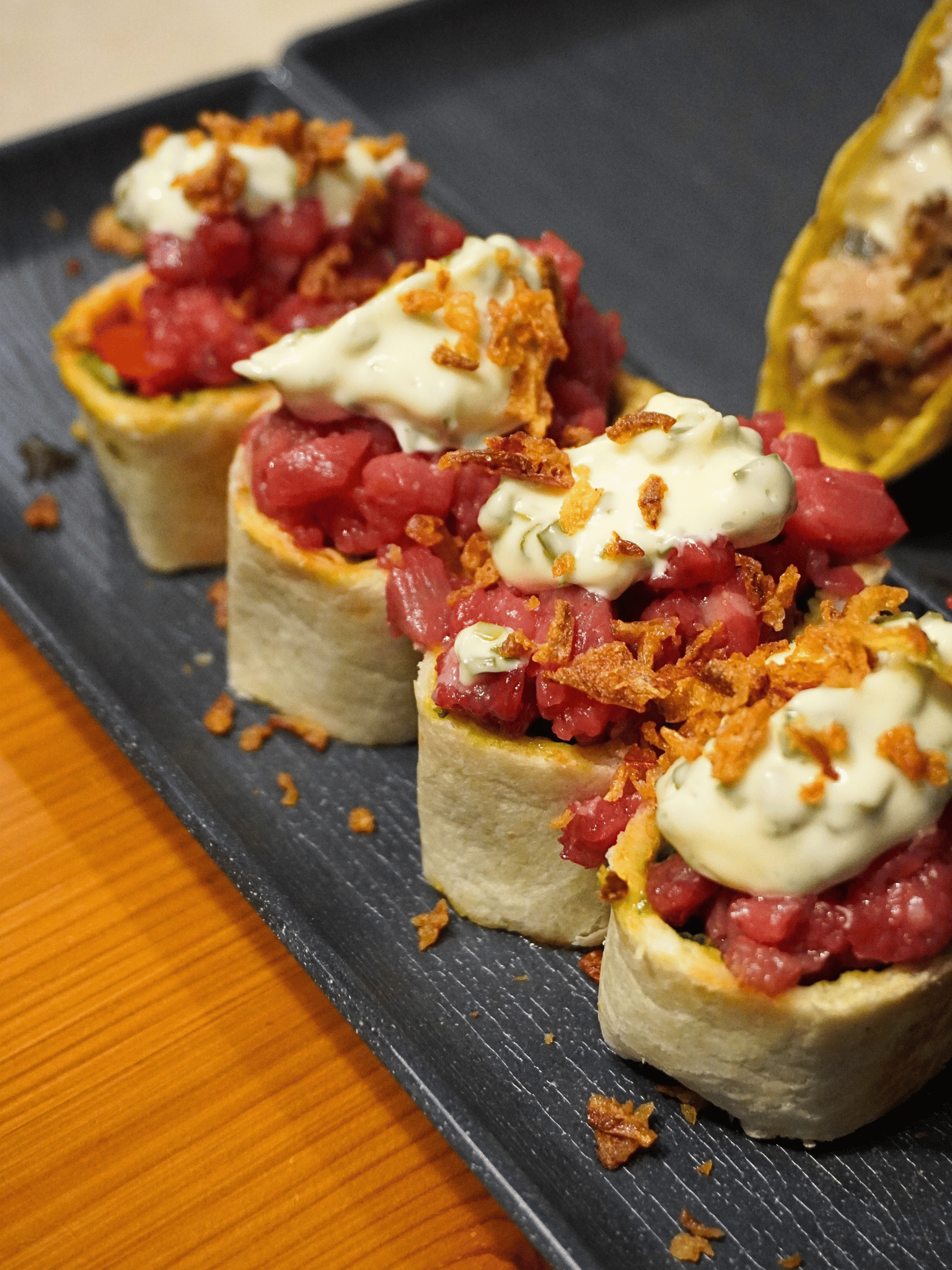 Roll di carne con tartare battuta al coltello, salsa e cipolla croccante