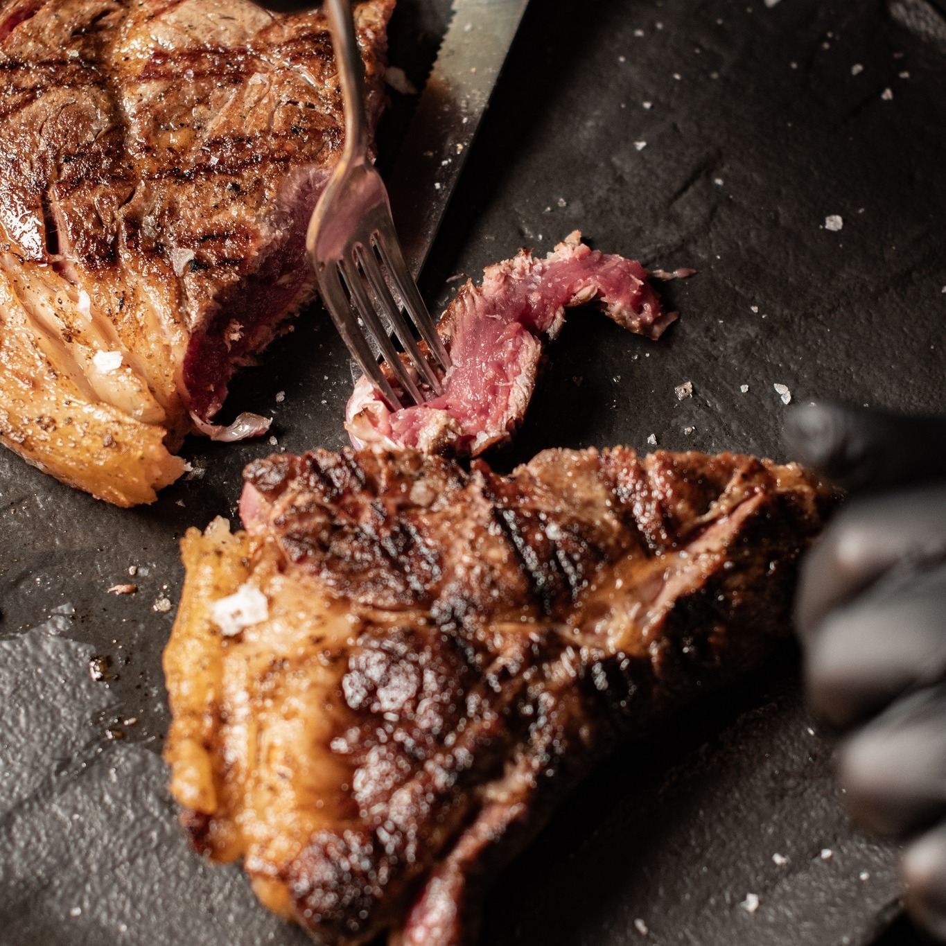 Taglio di carne alla brace cotto al sangue con forchetta e coltello da vicino