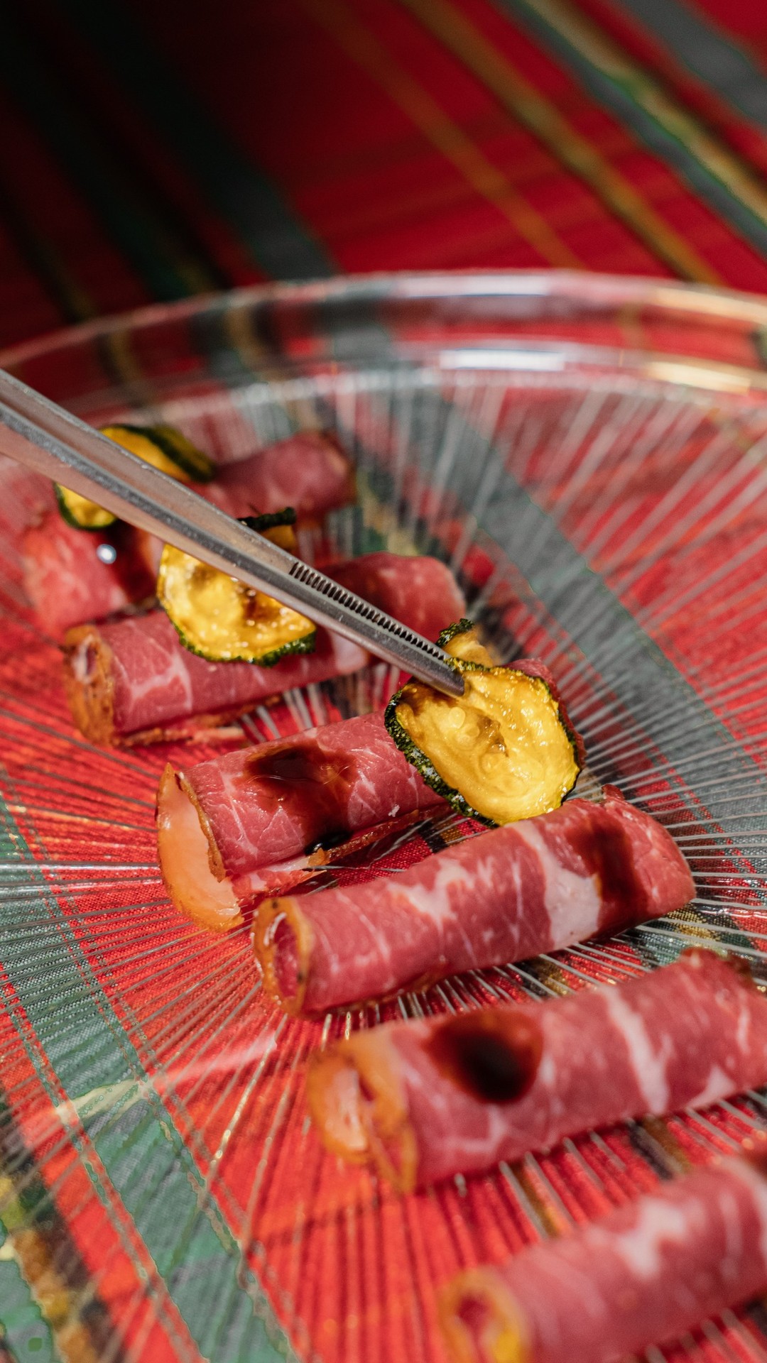 Involtini di carpaccio di manzo con zucchina croccante su piatto di vetro