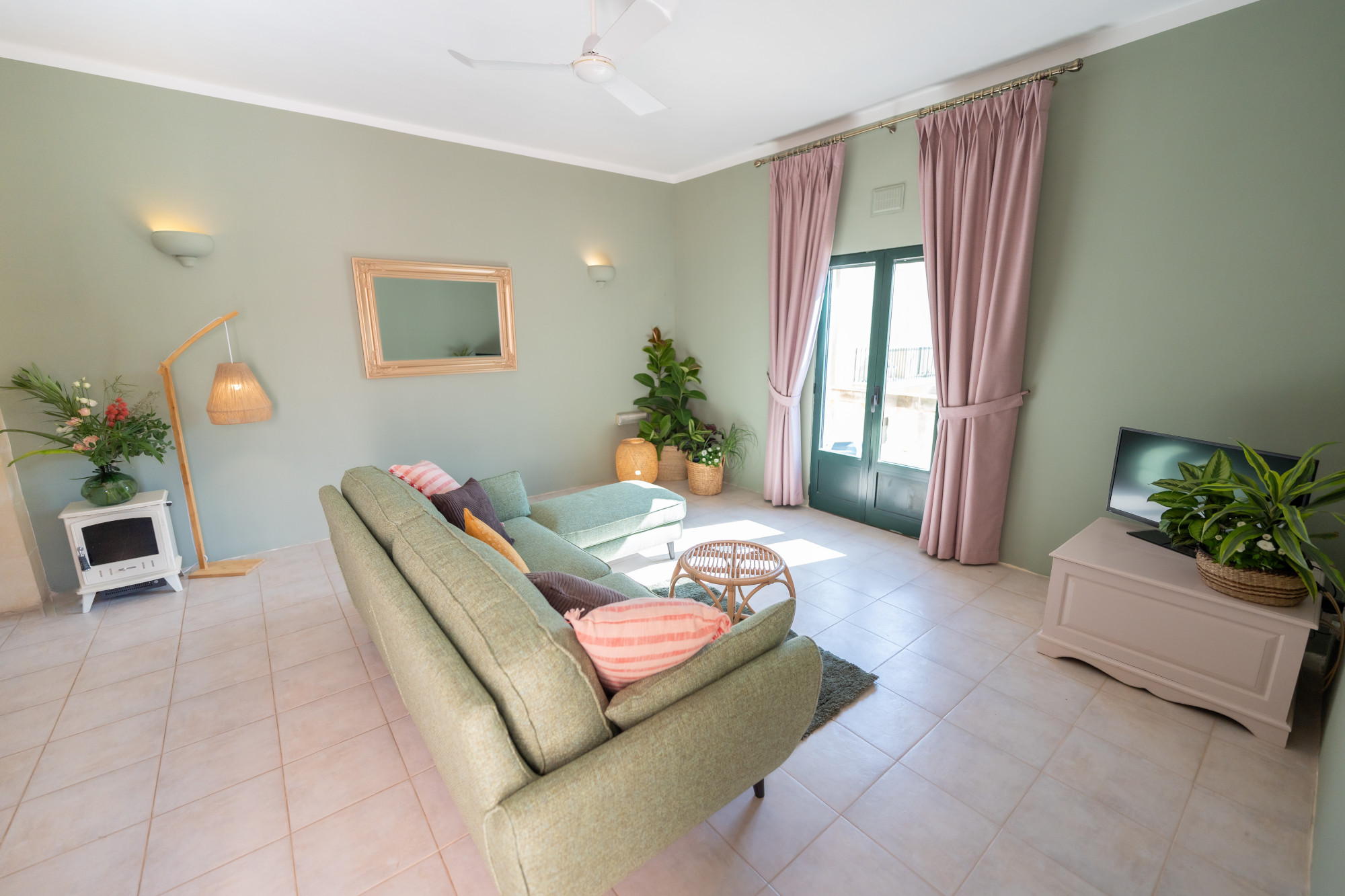 Bright apartment living room with comfortable seating, lush greenery and patio doors