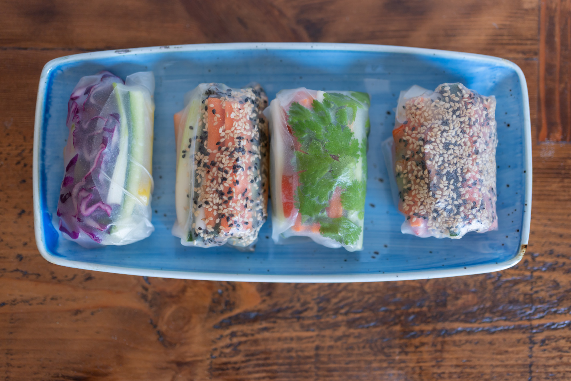 Freshly prepared nutrient-dense rainbow vegetable summer rolls with sesame garnish